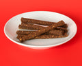 Beef Recipe Snack Sticks on a white plate on a red background