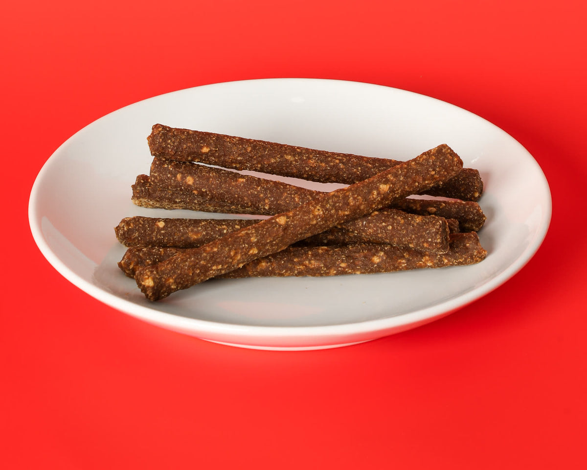 Beef Recipe Snack Sticks on a white plate on a red background