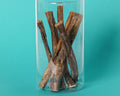 Water buffalo bully sticks standing in a glass jar on a teal background