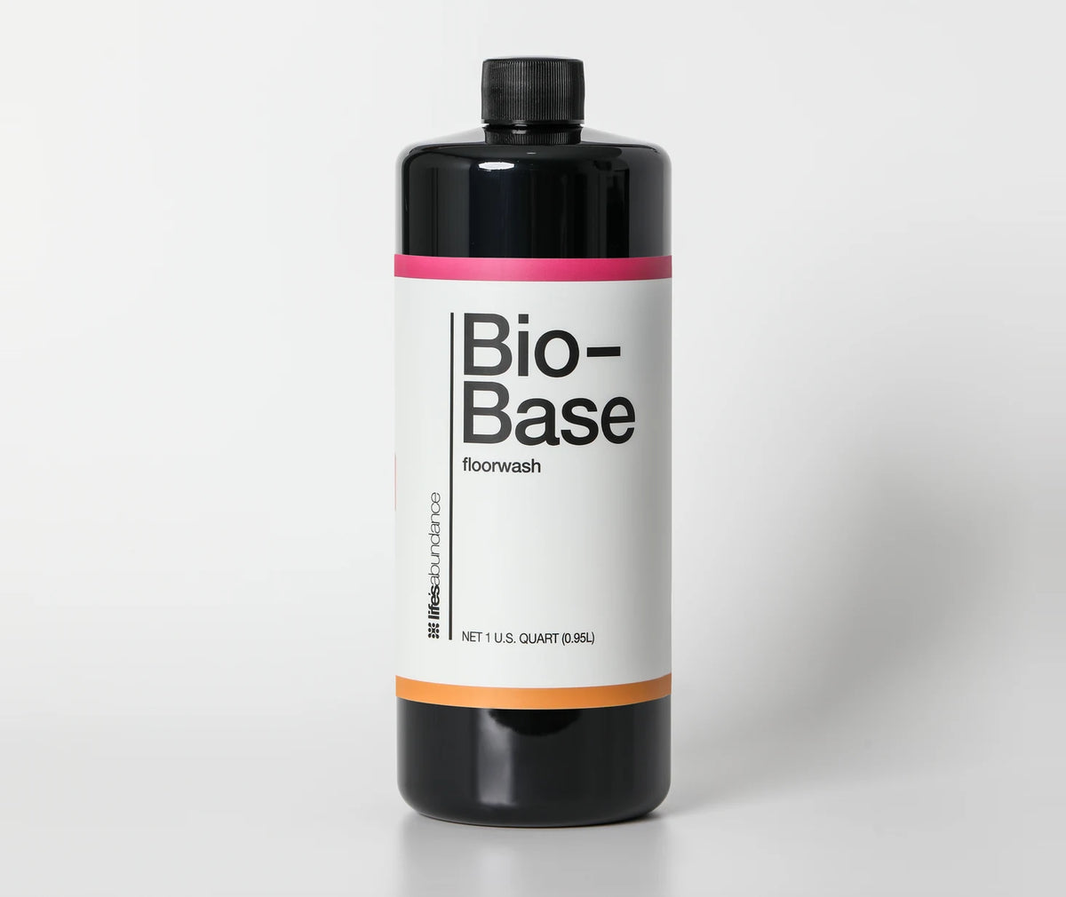 Bio-Base floorwash concentrate, black one-quart bottle with the pink and orange banded label, straight on against a pale studio seamless