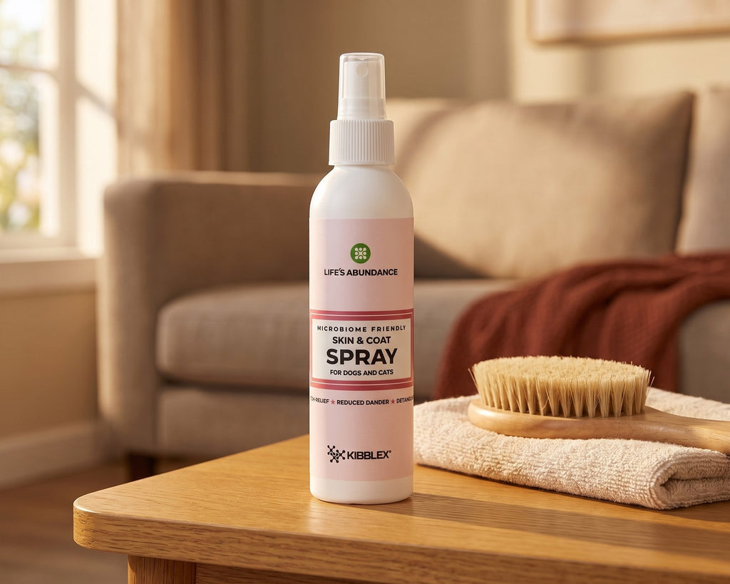 Skin & Coat Spray bottle for dogs and cats on a wooden coffee table beside a folded towel and a grooming brush