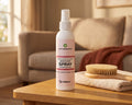 Skin & Coat Spray bottle for dogs and cats on a wooden coffee table beside a folded towel and a grooming brush