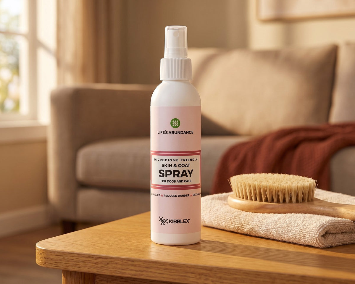 Skin & Coat Spray bottle for dogs and cats on a wooden coffee table beside a folded towel and a grooming brush