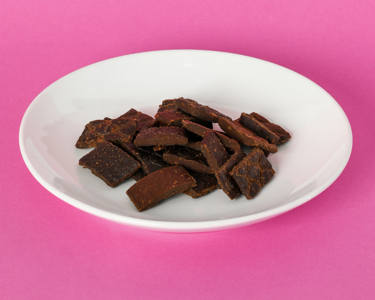 Grain Free Turkey & Berry Chewies on a white plate against a pink background